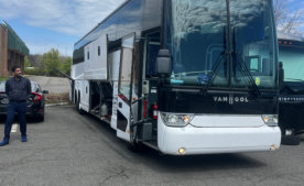 a white bus with a person beside