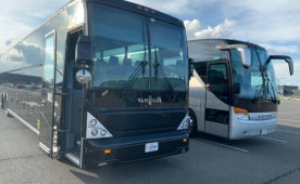 Two buses parked in a parking lot, ready to transport passengers