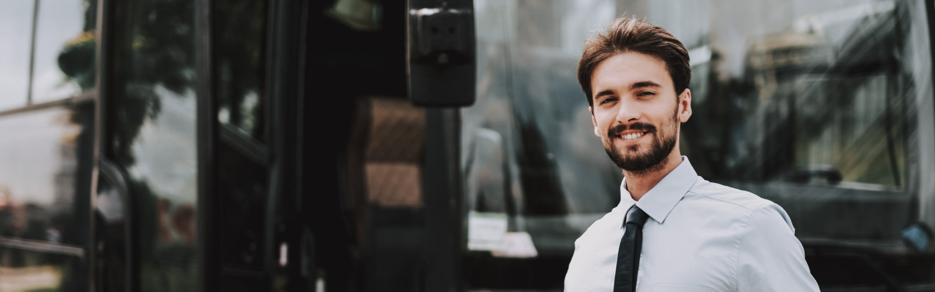 a man smiling with a black colored bus on the background